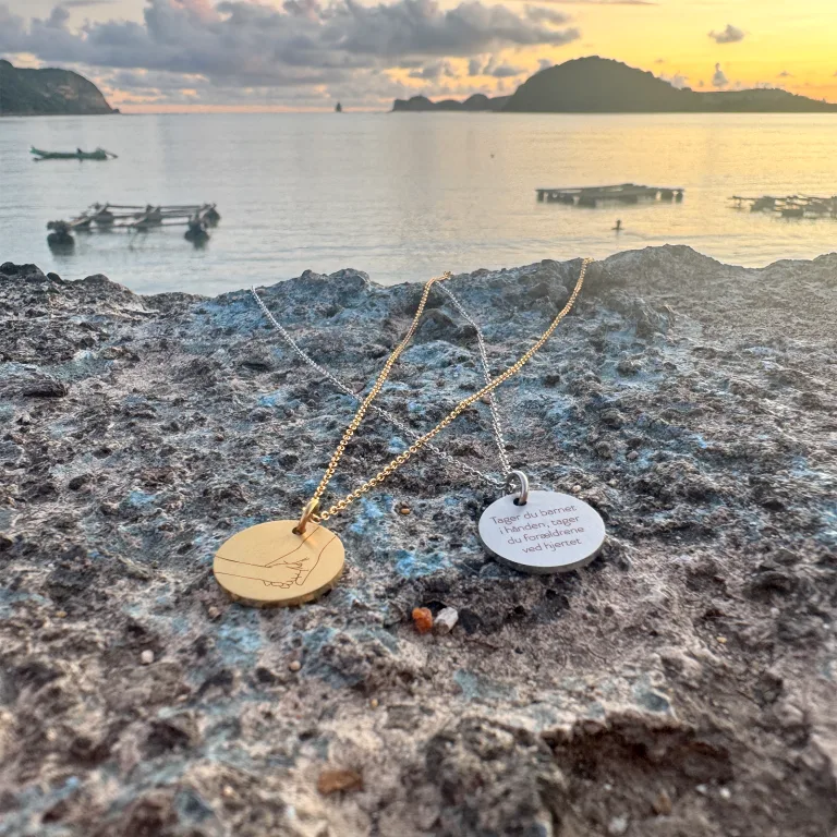 Förskollärare håller ett barn i handen – halsband